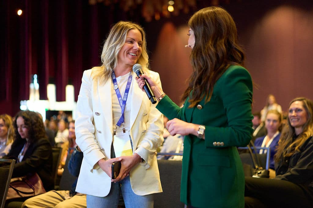 two women happy at a conference talking over a microphone during Q&A