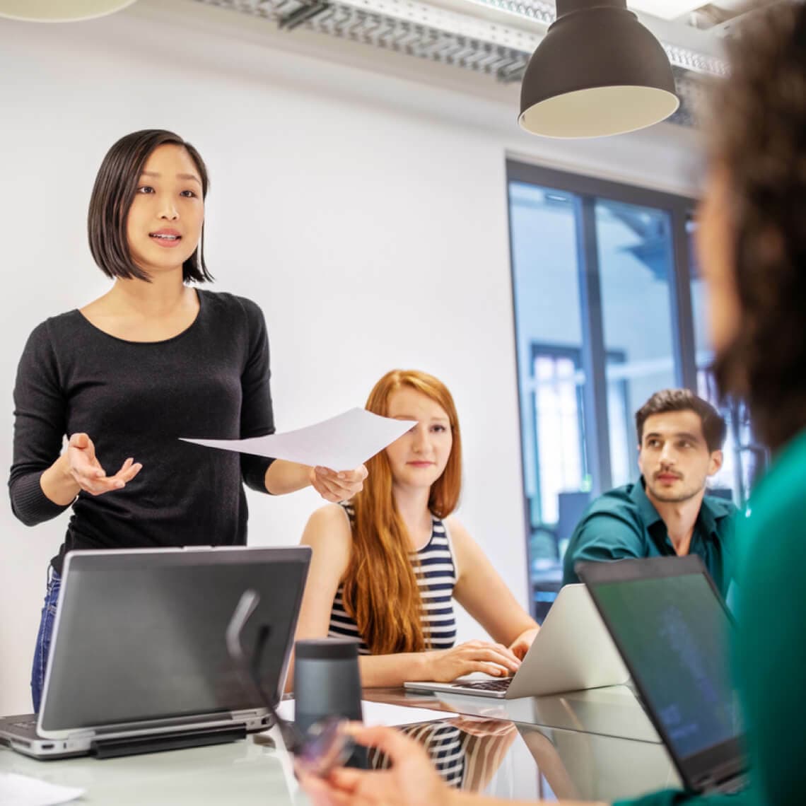 woman standing talking to group of coworkers in an office