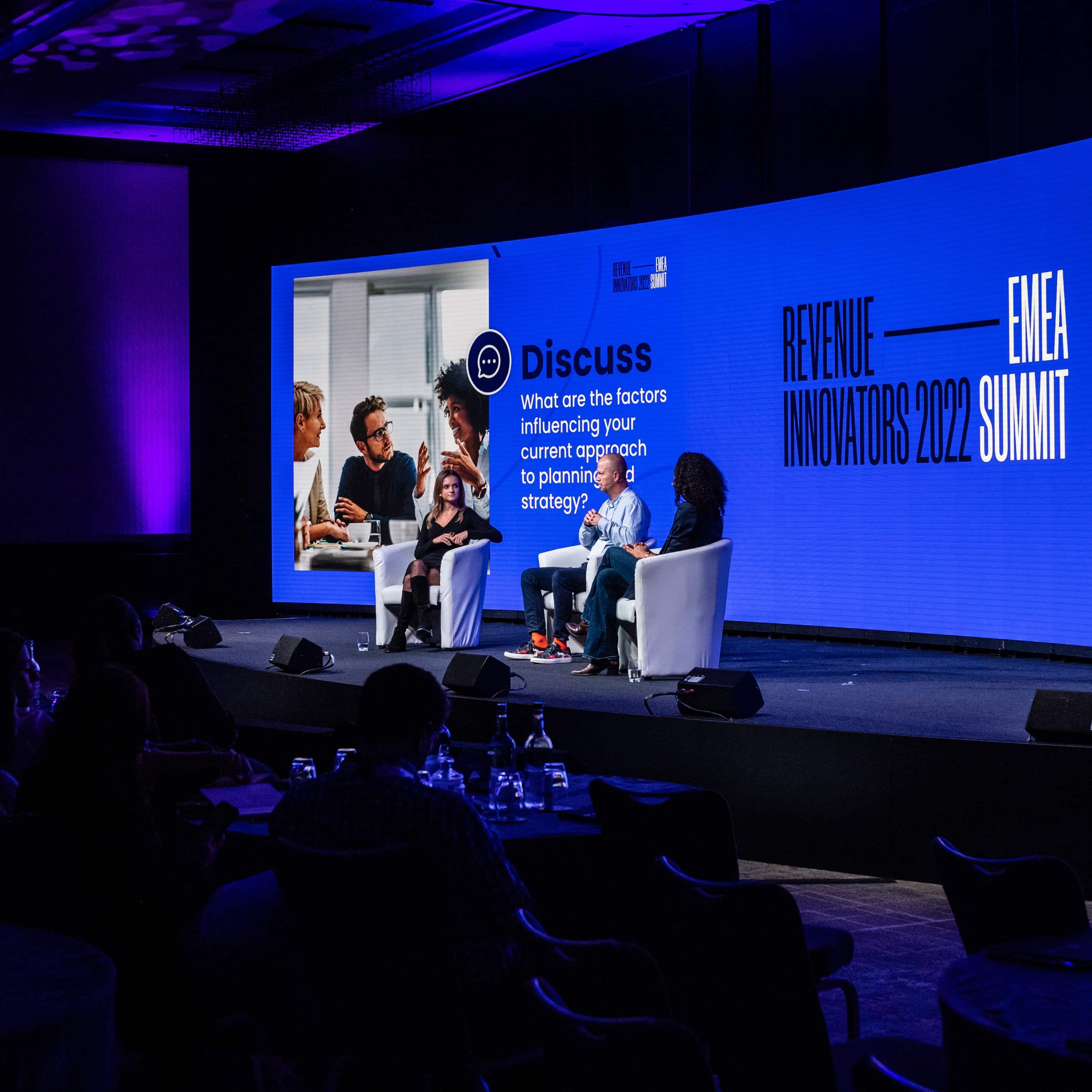 people sitting in chairs on a stage presenting