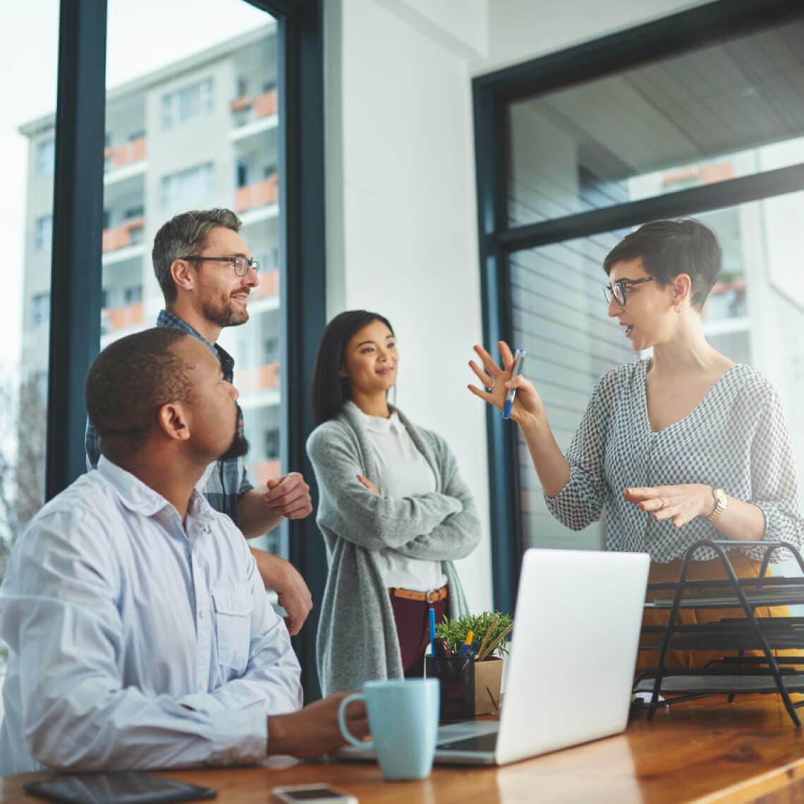 group of coworkers in an well lit office with big windows talking