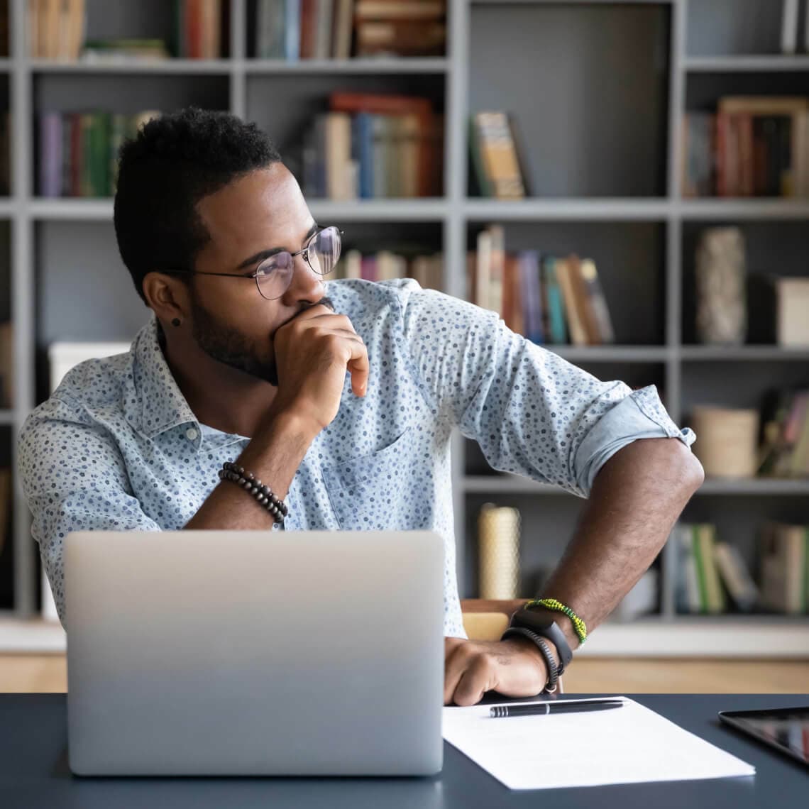 young man sitting in front of laptop, looking to the right