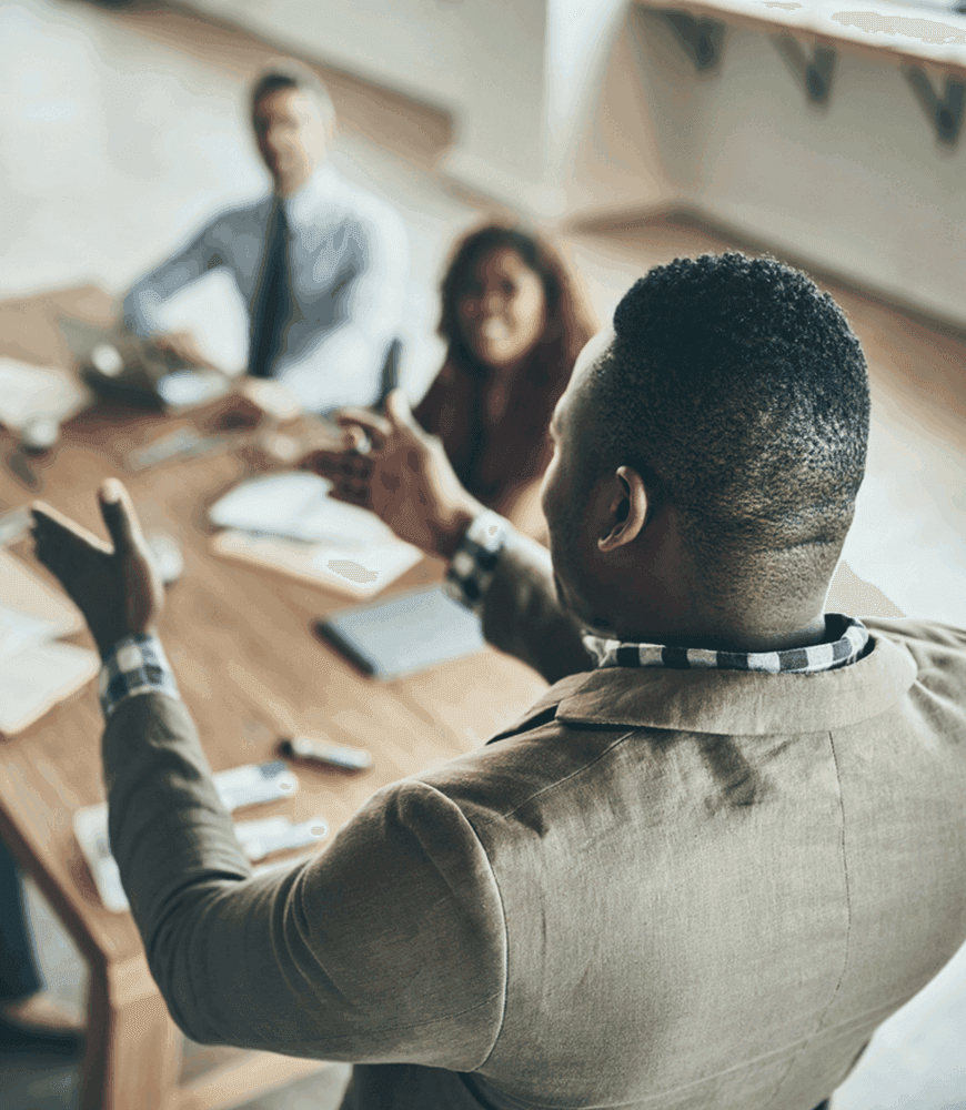 man standing addressing coworkers seated at a table