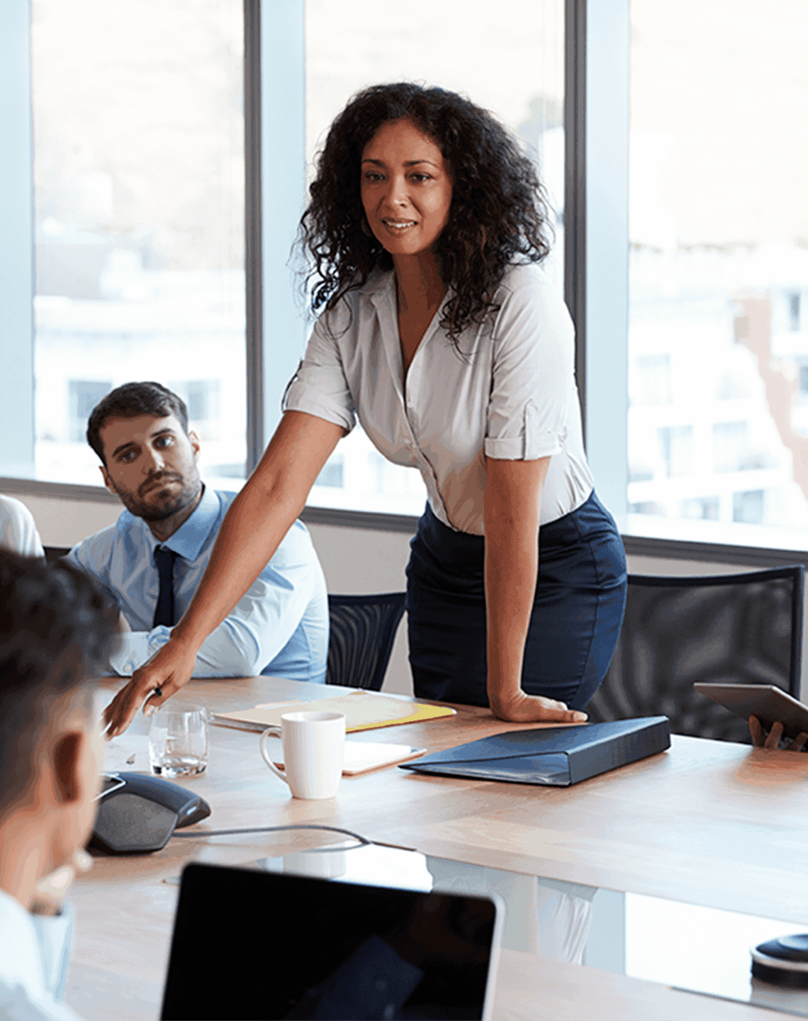 woman standing talking to group of people at a conference table