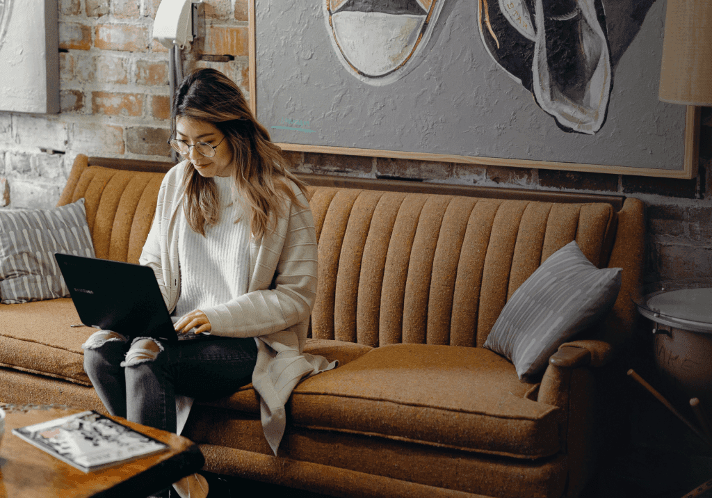 woman sitting on a couch in her apartment working on her laptop